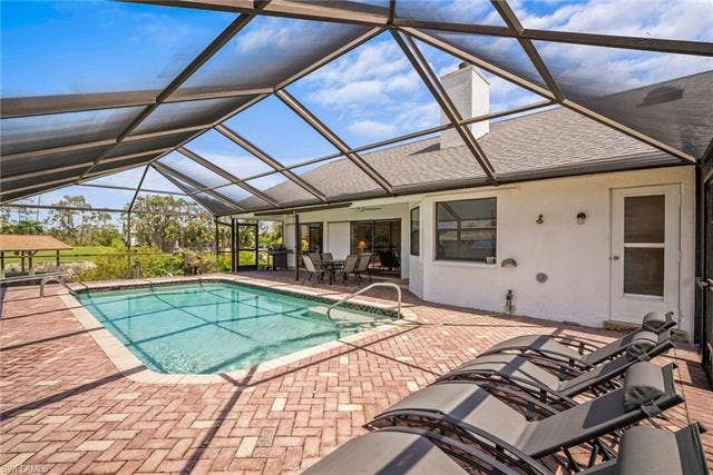 20640 Porthole Ct, Estero, FL 33928 Pool with a patio area, a lanai, a ceiling fan, and outdoor dining area