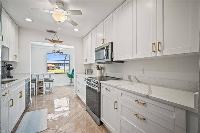 20640 Porthole Ct, Estero, FL 33928 Kitchen with white cabinets, recessed lighting, visible vents, light stone countertops, and appliances with stainless steel finishes