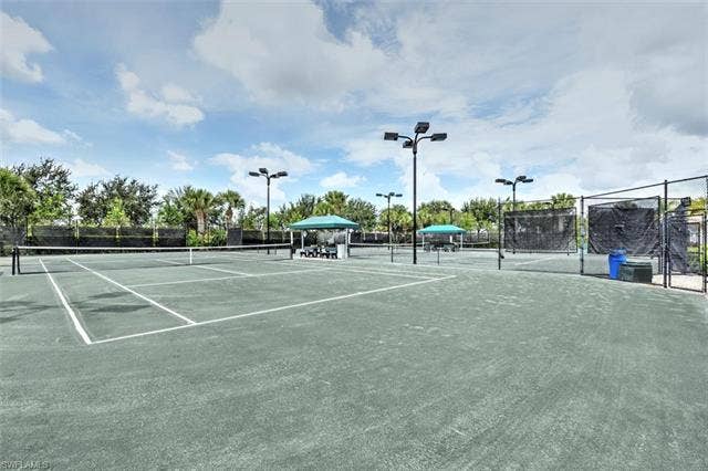 15059 Blue Marlin Ter, Bonita Springs, FL 34135 Multiple hard-surface tennis courts featuring perimeter fencing, overhead lighting, and covered seating areas