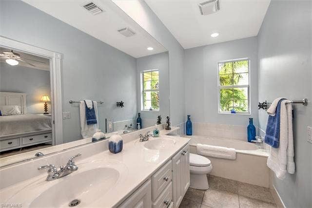 15059 Blue Marlin Ter, Bonita Springs, FL 34135 Dual vanity with undermount sinks and chrome fixtures, built-in soaking tub with tile surround, and a clear window seperate double walk in shower on other side all part of en suite upper main BR WITH BLACLINY
