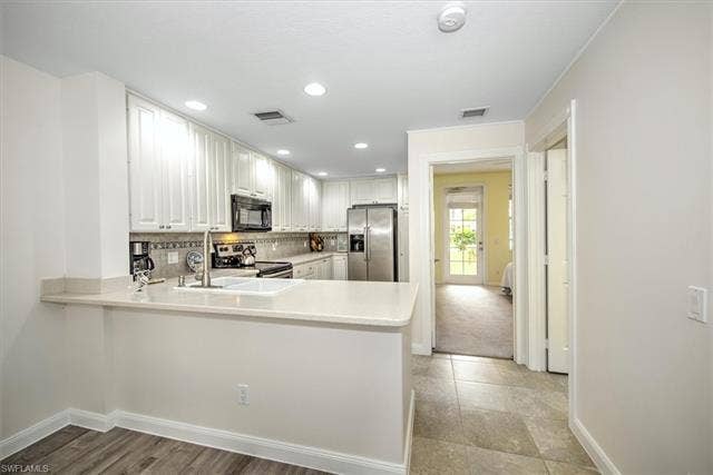 15059 Blue Marlin Ter, Bonita Springs, FL 34135 White upper and lower cabinetry, stainless steel appliances, light-toned countertops, and recessed lighting main floor bedroom with Bath
