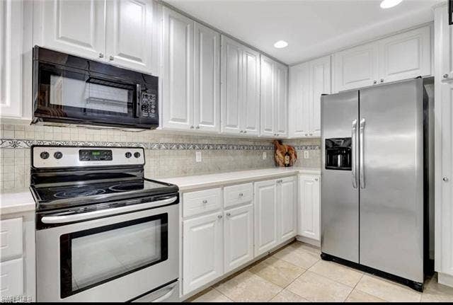 15059 Blue Marlin Ter, Bonita Springs, FL 34135 White cabinetry with silver-tone hardware, stainless steel appliances, light-toned countertop, tile backsplash with decorative accent, and recessed lighting