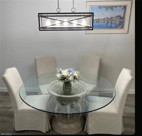 15059 Blue Marlin Ter, Bonita Springs, FL 34135 Round glass top stone base with 6 elegant chairs Rectangular chandelier with exposed bulbs, light gray wall paint, and wood-finish flooring