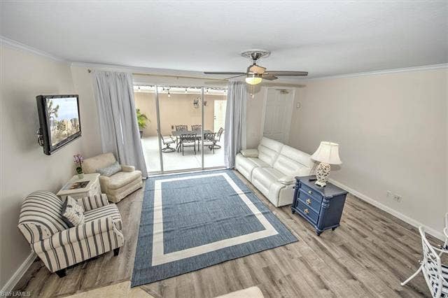 15059 Blue Marlin Ter, Bonita Springs, FL 34135 Wood-color water proof vynil finish flooring, ceiling fan with integrated lighting,, and sliding glass door leading to a paved outdoor patio with an outdoor dining set 2 swivel 4 chairs excluding nautical chair