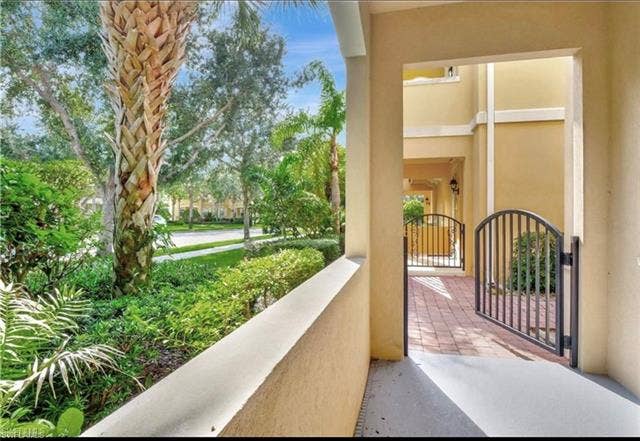 15059 Blue Marlin Ter, Bonita Springs, FL 34135 Off main BR Lush landscaping featuring mature palm trees, decorative wrought iron gates, and a red paver walkway