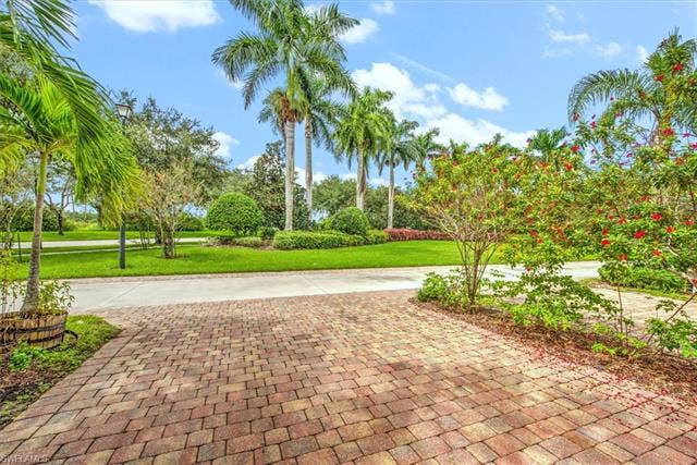 15059 Blue Marlin Ter, Bonita Springs, FL 34135 From the garage views Most private property in the street . Paver driveway with a curved design, bordered by mature palm trees and lush landscaping