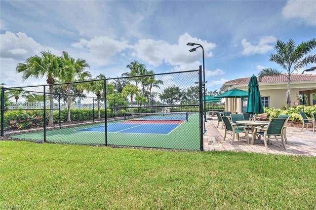 15059 Blue Marlin Ter, Bonita Springs, FL 34135 3pickleball courts enclosed by a black chain-link fence, surrounded by lush landscaping and palm trees
