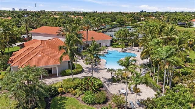 19600 Maddelena Cir, Estero, FL 33967 Expansive outdoor amenities featuring a freeform swimming pool, multiple tennis courts, and mature tropical landscaping
