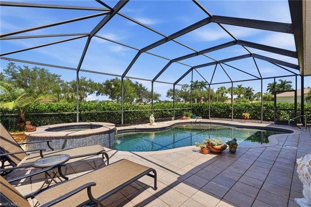 19600 Maddelena Cir, Estero, FL 33967 Screened outdoor living area featuring a swimming pool, integrated spa, and paver decking