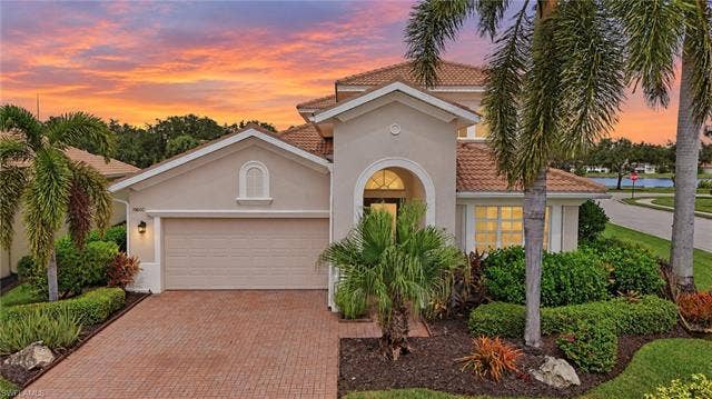 19600 Maddelena Cir, Estero, FL 33967 Stucco exterior with a tile roof, arched entryway, and an attached garage