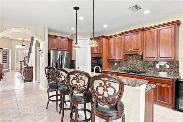 19600 Maddelena Cir, Estero, FL 33967 Kitchen featuring extensive wood cabinetry, granite countertops, tile backsplash, and stainless steel appliances
