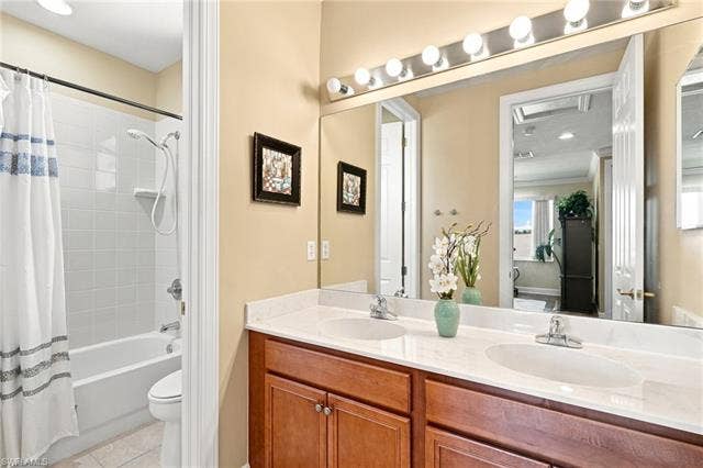 19600 Maddelena Cir, Estero, FL 33967 Bathroom featuring a double vanity with wood-finish cabinetry, a large mirror, and a tub with an integrated shower