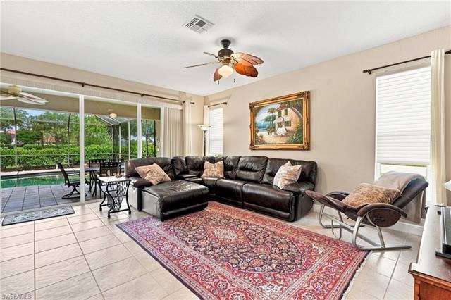 19600 Maddelena Cir, Estero, FL 33967 Spacious living area featuring tile flooring, ceiling fan, and large windows with privacy blinds