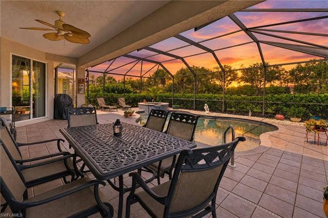 19600 Maddelena Cir, Estero, FL 33967 Screened lanai featuring a ceiling fan, a freeform pool, a built-in spa, and a tiled patio
