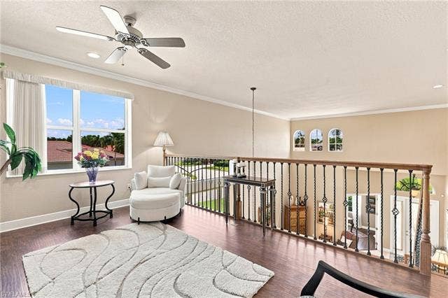 19600 Maddelena Cir, Estero, FL 33967 Upper-level landing featuring wood-finish flooring, a ceiling fan, and decorative wrought iron railing