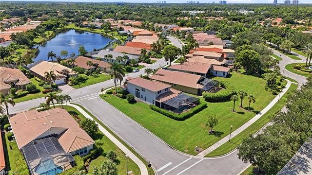 19600 Maddelena Cir, Estero, FL 33967 Lush green landscaping and mature trees complement the neighborhood's architecture, featuring terracotta-tiled roofs and screened pools