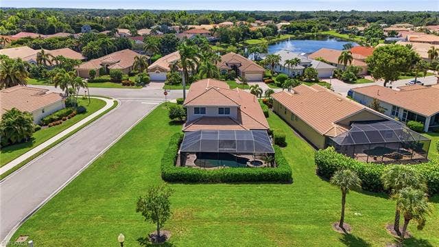 19600 Maddelena Cir, Estero, FL 33967 Aerial perspective of a neighborhood featuring residential structures with tile roofs and manicured landscaping