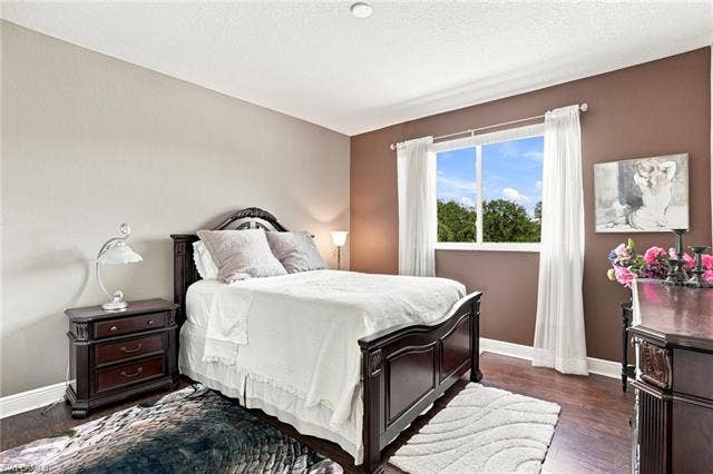 19600 Maddelena Cir, Estero, FL 33967 Wood-finish flooring, white trim, and a window with white drapes