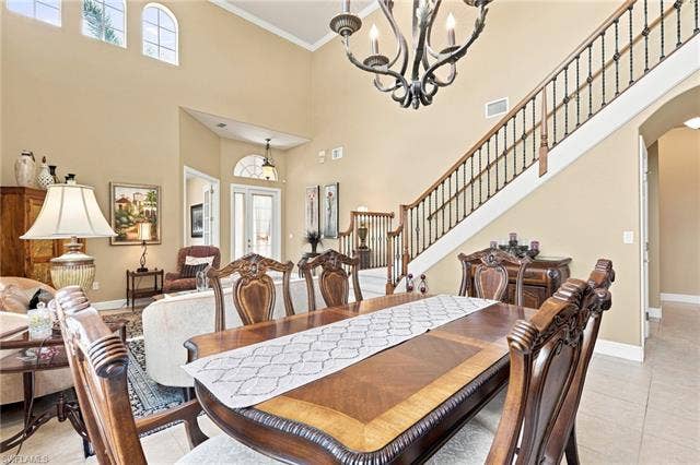 19600 Maddelena Cir, Estero, FL 33967 Vaulted ceiling with decorative chandelier, arched windows, grand staircase with wrought iron balusters, wood-finish flooring, and double French doors