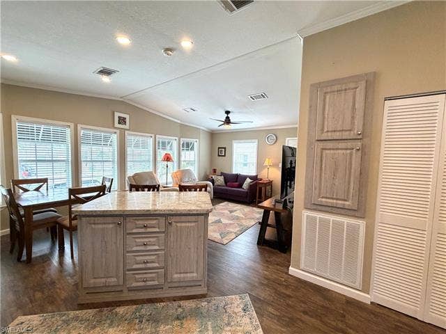 4710 W Lafayette Ln, Estero, FL 33928 Recessed lighting, wood-finish flooring, kitchen island with stone countertop, multiple windows, and vaulted ceiling