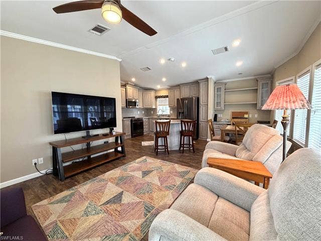 4710 W Lafayette Ln, Estero, FL 33928 Open-concept living space with wood-finish flooring, crown molding, a ceiling fan, and recessed lighting