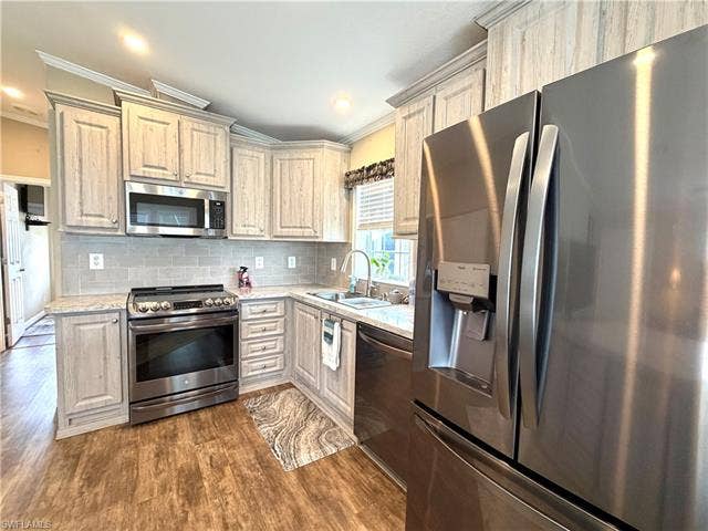 4710 W Lafayette Ln, Estero, FL 33928 Kitchen featuring wood-finish flooring, stainless steel appliances, light-toned cabinetry, light-colored countertops, and a subway tile backsplash