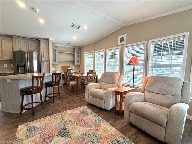 4710 W Lafayette Ln, Estero, FL 33928 Open-concept living space with wood-finish flooring, vaulted ceilings, recessed lighting, and multiple windows with blinds