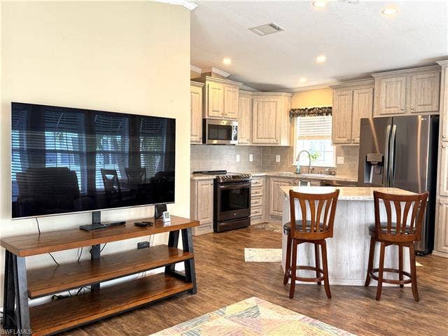 4710 W Lafayette Ln, Estero, FL 33928 Kitchen with wood-finish flooring, recessed lighting, light-toned cabinetry, stainless steel appliances, and a central island