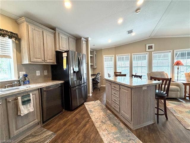 4710 W Lafayette Ln, Estero, FL 33928 Kitchen featuring wood-finish cabinetry, stainless steel appliances, a tiled backsplash, a kitchen island with seating, and wood-finish flooring