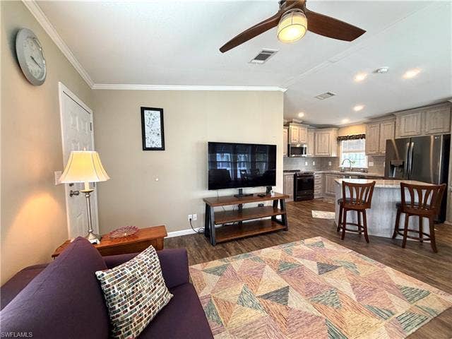4710 W Lafayette Ln, Estero, FL 33928 Open-concept living area with wood-finish flooring, a ceiling fan, crown molding, and recessed lighting