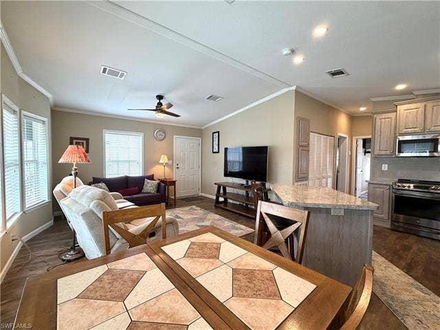 4710 W Lafayette Ln, Estero, FL 33928 Integrated kitchen and living area featuring wood-finish flooring, a kitchen island with a stone-finish countertop, and stainless steel appliances