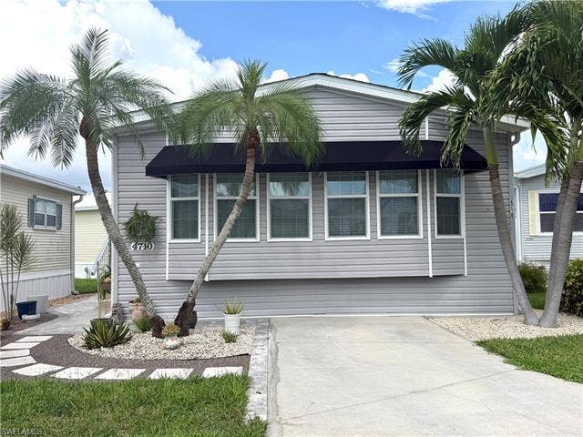 4710 W Lafayette Ln, Estero, FL 33928 Gray siding exterior with multiple windows, featuring a black fabric awning