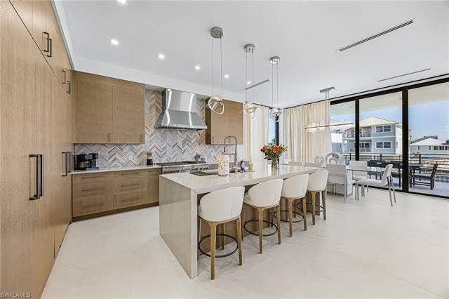 455 Palermo Cir, Fort Myers Beach, FL 33931 Kitchen with modern cabinets, light stone counters, decorative light fixtures, decorative backsplash, and floor to ceiling windows - Virtually Edited Image