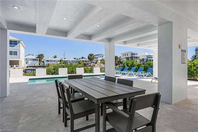 455 Palermo Cir, Fort Myers Beach, FL 33931 View of patio with a community pool, a residential view, and outdoor dining area - Virtually Edited Image