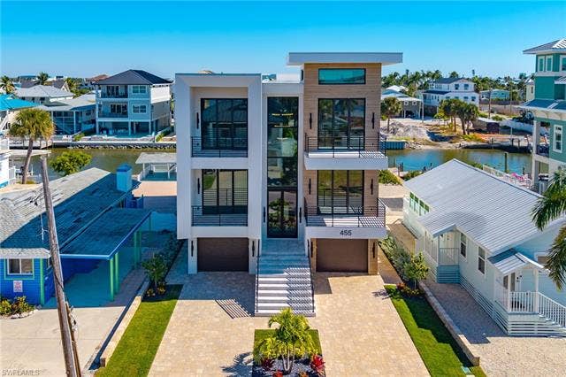 455 Palermo Cir, Fort Myers Beach, FL 33931 Contemporary house with a residential view, a balcony, a water view, and an attached garage - Virtually Edited Image