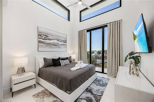 455 Palermo Cir, Fort Myers Beach, FL 33931 Bedroom with multiple windows, access to exterior, and a towering ceiling - Virtually Edited Image