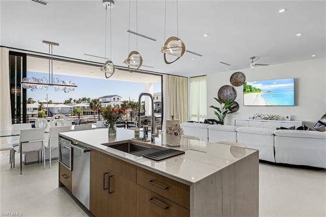455 Palermo Cir, Fort Myers Beach, FL 33931 Kitchen featuring brown cabinetry, hanging light fixtures, modern cabinets, open floor plan, and a kitchen island with sink - Virtually Edited Image