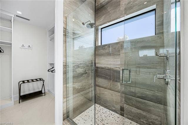 455 Palermo Cir, Fort Myers Beach, FL 33931 Bathroom featuring a stall shower, tile patterned floors, and a spacious closet - Virtually Edited Image
