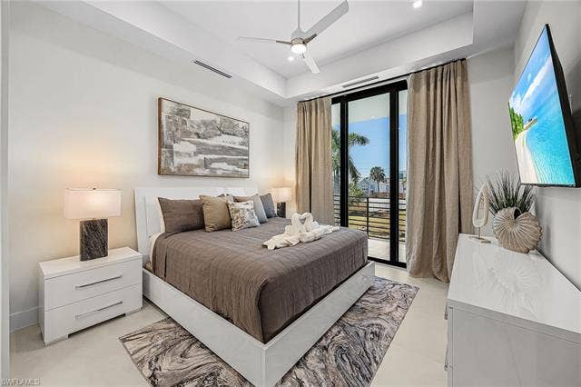 455 Palermo Cir, Fort Myers Beach, FL 33931 Bedroom featuring access to exterior, a ceiling fan, a raised ceiling, and recessed lighting - Virtually Edited Image