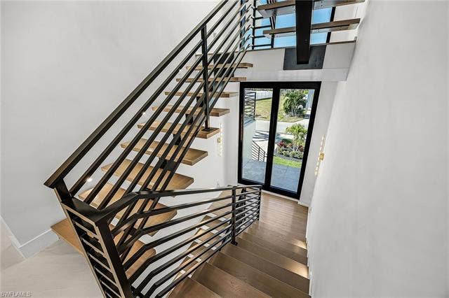 455 Palermo Cir, Fort Myers Beach, FL 33931 Staircase with hardwood / wood-style flooring and a towering ceiling - Virtually Edited Image
