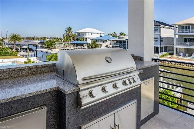 455 Palermo Cir, Fort Myers Beach, FL 33931 View of patio with an outdoor kitchen and a residential view - Virtually Edited Image
