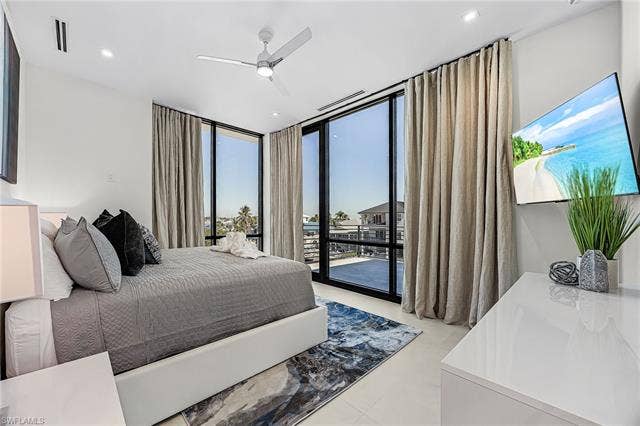 455 Palermo Cir, Fort Myers Beach, FL 33931 Bedroom with floor to ceiling windows, access to exterior, and ceiling fan - Virtually Edited Image