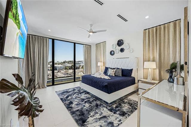 455 Palermo Cir, Fort Myers Beach, FL 33931 Bedroom featuring expansive windows, a ceiling fan, and light tile patterned floors - Virtually Edited Image