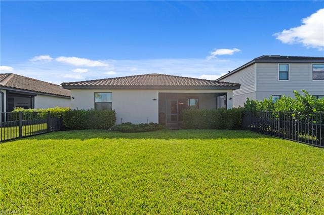 19712 The Place Blvd, Estero, FL 33928 Expansive green lawn with mature perimeter landscaping and black fencing