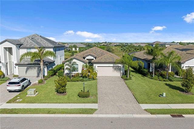 19712 The Place Blvd, Estero, FL 33928 Single-story residence featuring a tile roof, an integrated garage, and a paver driveway