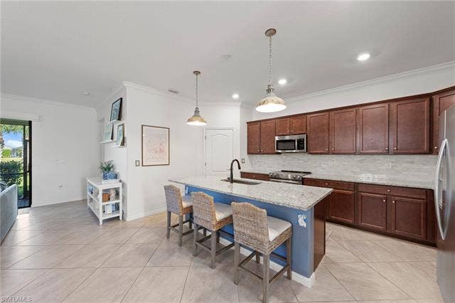 19712 The Place Blvd, Estero, FL 33928 Expansive kitchen featuring a large island with seating, stainless steel appliances, abundant cabinetry, and light-toned tile flooring
