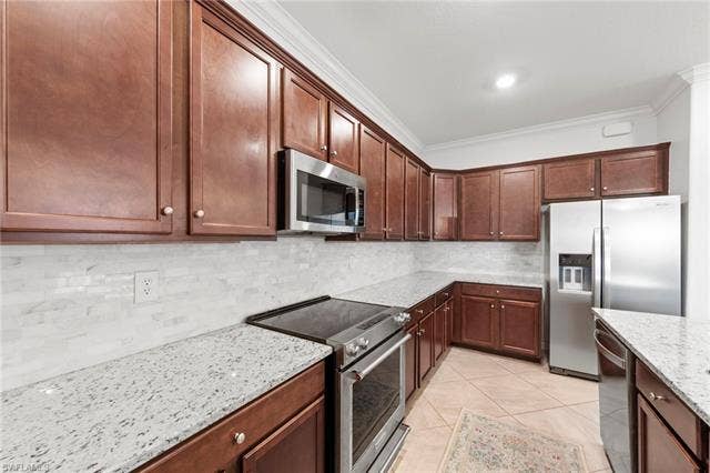 19712 The Place Blvd, Estero, FL 33928 Kitchen featuring wood-finish cabinetry, stainless steel appliances, granite countertops, and a subway tile backsplash