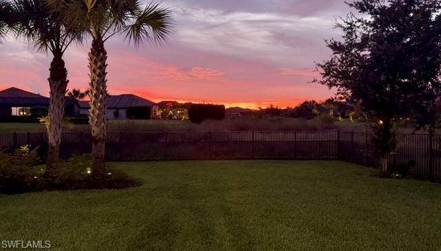 19712 The Place Blvd, Estero, FL 33928 Expansive backyard featuring a manicured lawn, established palm trees, and perimeter fencing