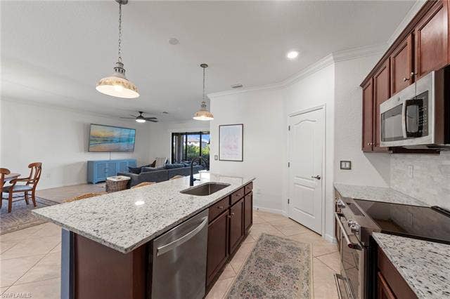 19712 The Place Blvd, Estero, FL 33928 Kitchen island with an undermount sink, granite countertops, stainless steel appliances, and wood-finish cabinetry