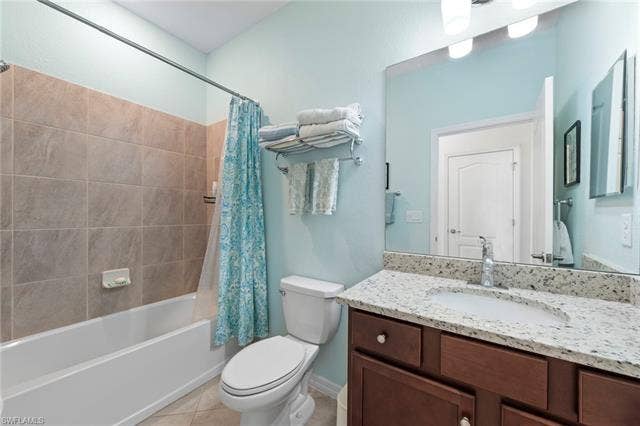 19712 The Place Blvd, Estero, FL 33928 White bathtub with tile surround, wood-finish vanity with an integrated sink, polished chrome faucet, and expansive wall-mounted mirror